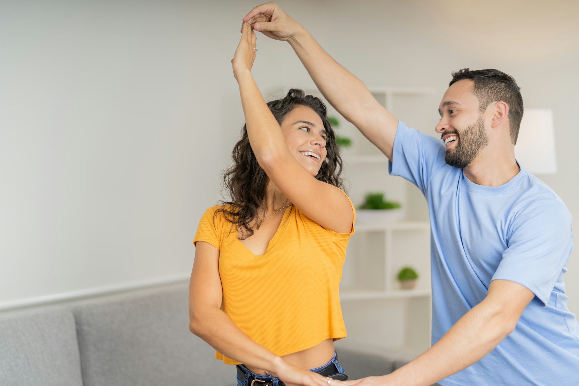 Couple smiling and dancing bachata at home
